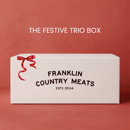 White box with red bow labeled 'The Festive Trio Box' by Franklin Country Meats on a red background